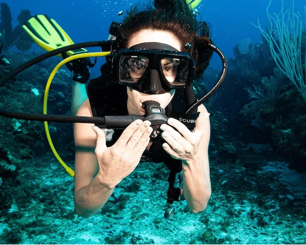 Beginner scuba diver staying calm while learning how to clear diving mask underwater.