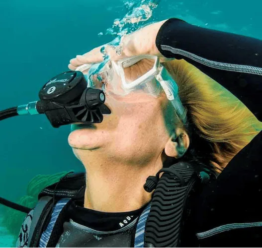 Diver pressing the top frame of the mask to create a proper seal before clearing water.
